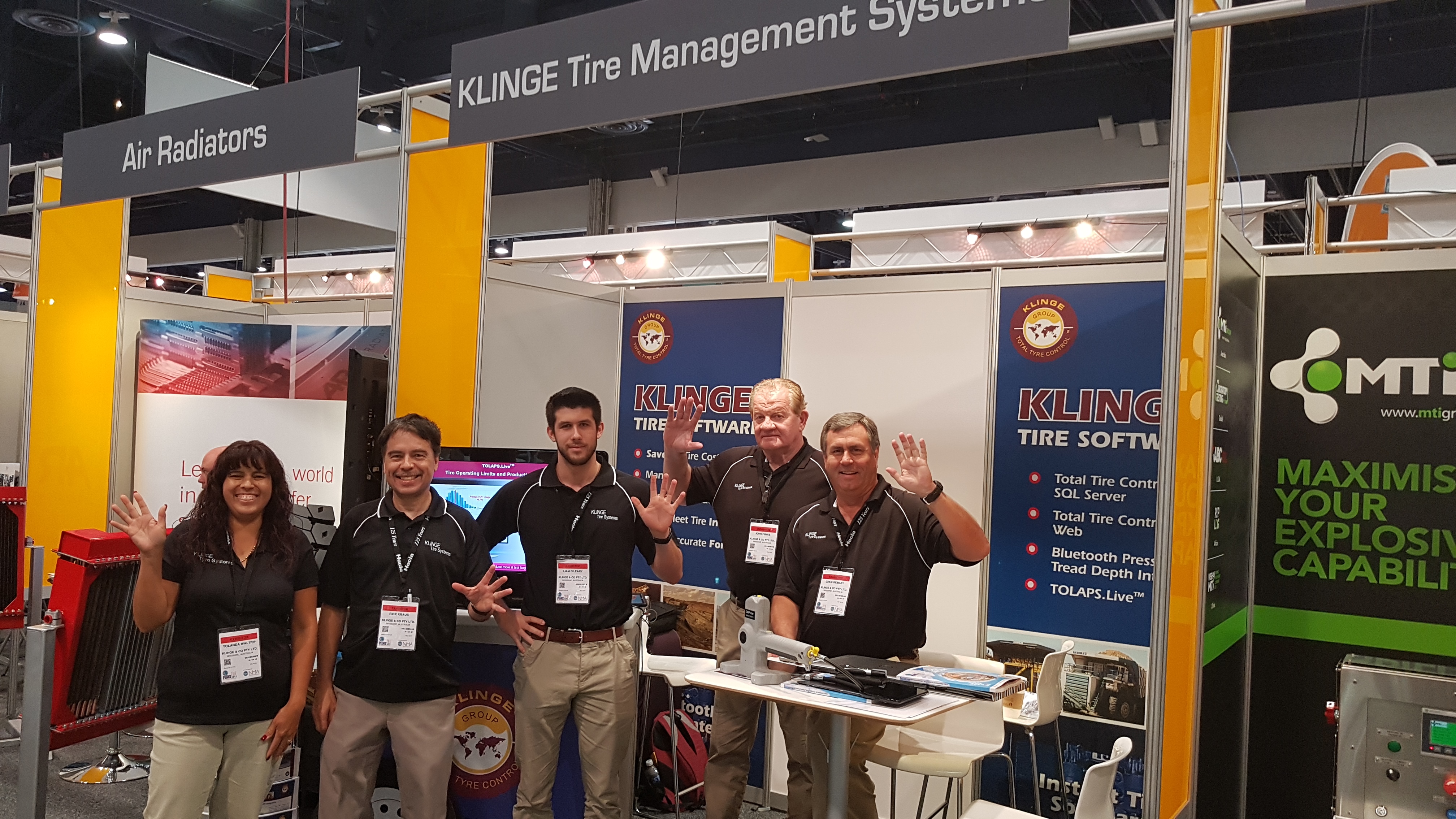 A group of people standing in front of the Klinge booth at a trade show.