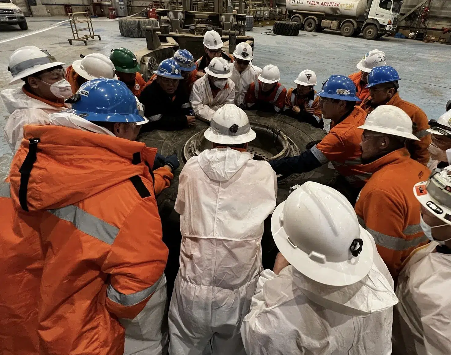A group of workers are standing around a large tire equipped with OTR tyre management systems.