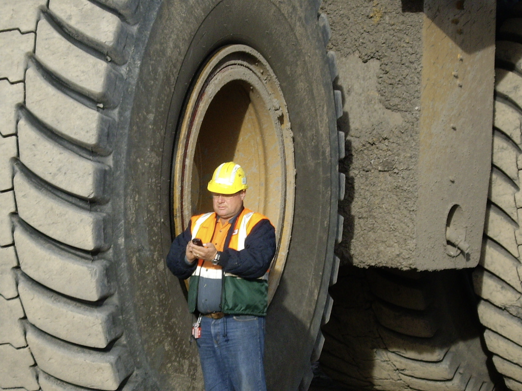 A man standing off the road in a large tire.