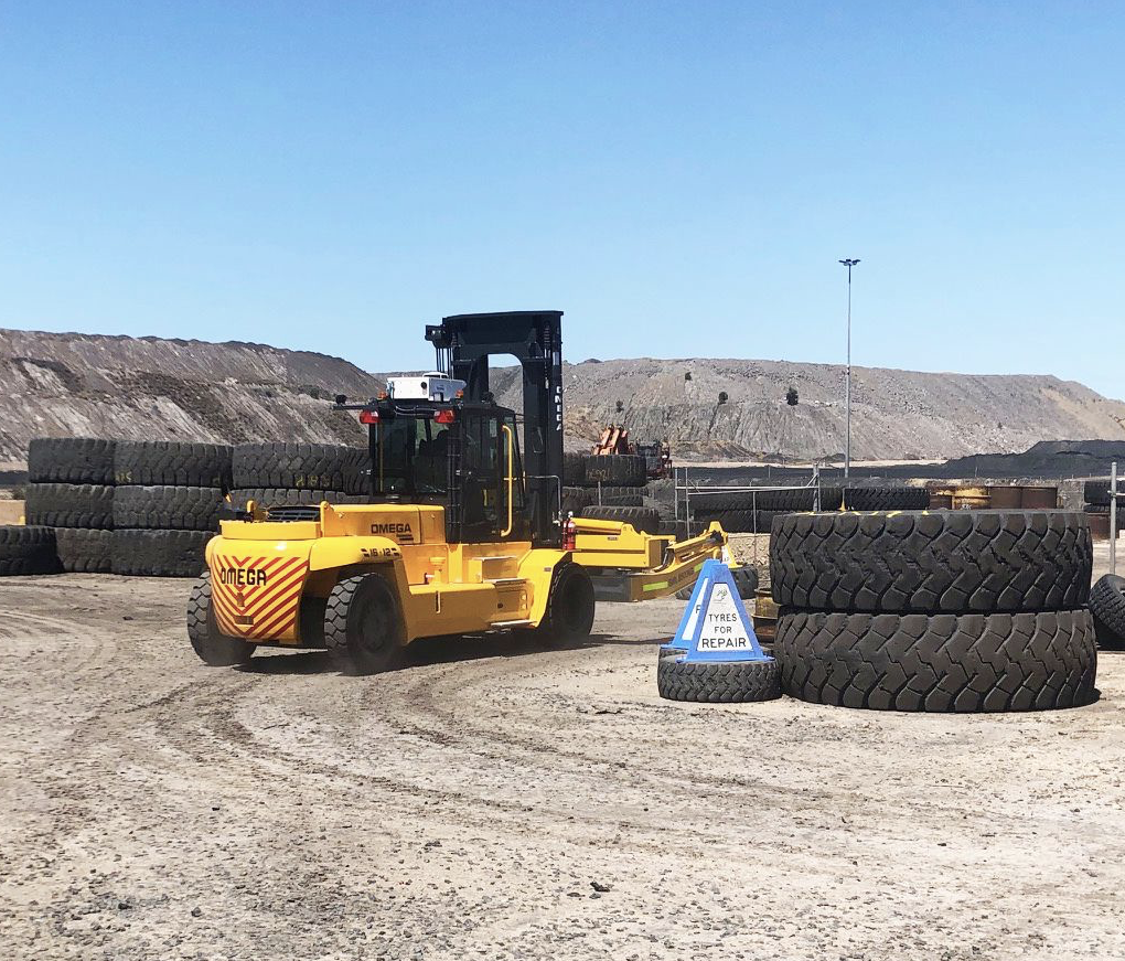 An off the road forklift in a dirt area with tires.