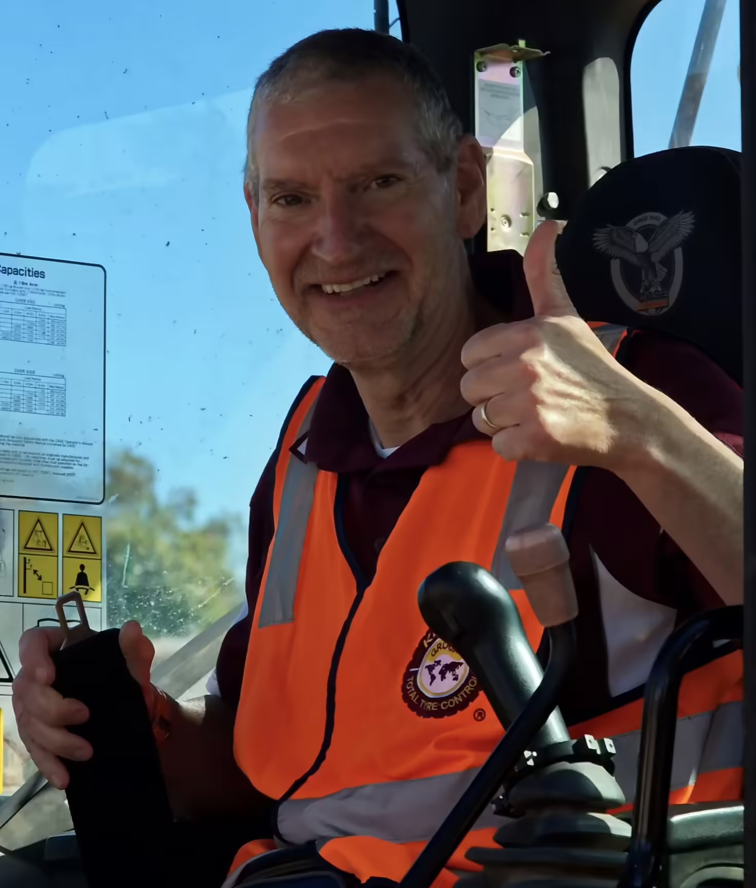 A man in an orange vest giving a thumbs up while working on off the road (OTR) tyre management systems.