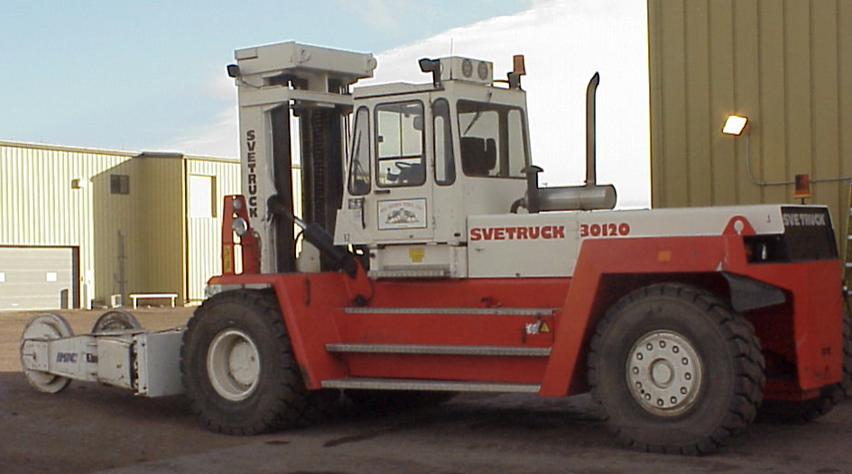 A red and white forklift truck equipped with tyre management systems parked in front of a building.