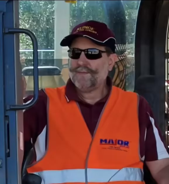 A man in an orange vest operating an off the road bulldozer.