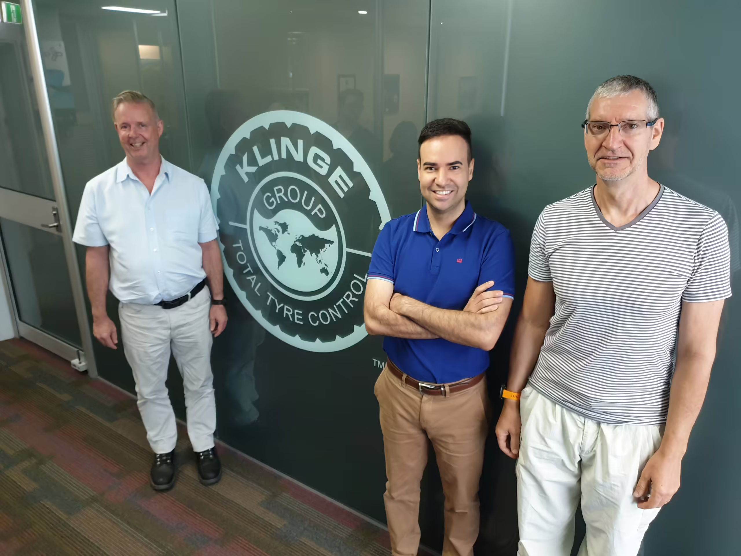 Three Men Standing In Front Of A Wall
